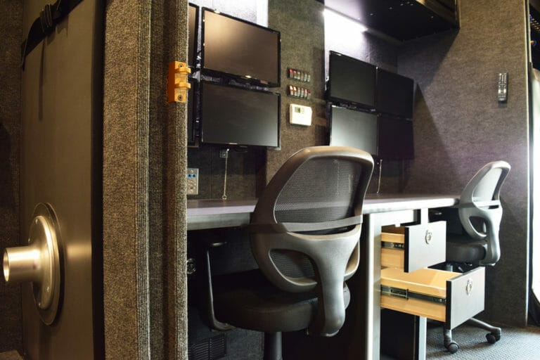 Several computers and two chairs inside a mobile command center vehicle
