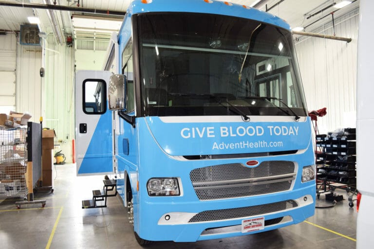 Front of a blue bloodmobile bus inside a garage