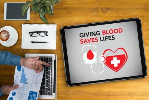 Overview of a desk with hands and marketing material for a blood drive